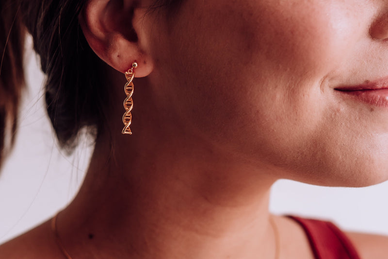 Close-up of a woman wearing gold earrings and a necklace with a blurred background