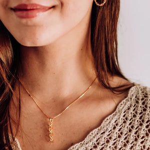 Model wearing DNA double helix necklace in gold - chemistry inspired jewellery gift for science lovers 