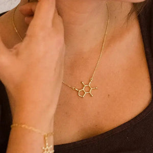 Model wearing caffeine molecule necklace in gold - science inspired jewellery gift for coffee lovers