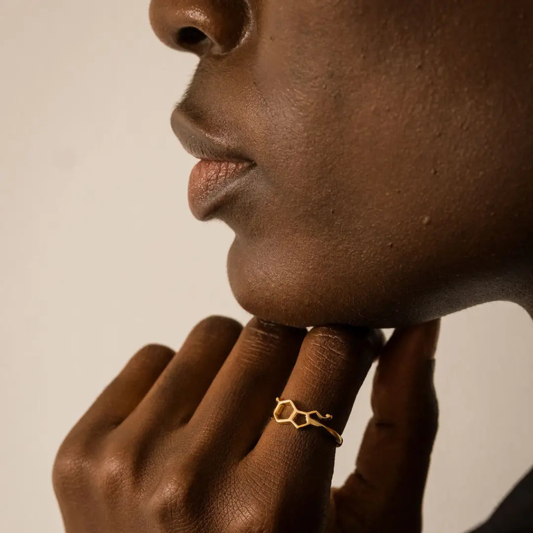 Model wearing serotonin molecule ring in gold - chemistry inspired jewellery for science lovers