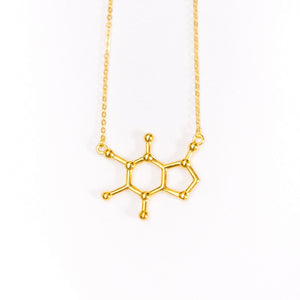 Gold necklace with a molecular design pendant on a white background