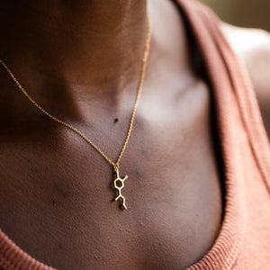 Model wearing adrenaline molecule necklace in gold - chemistry inspired jewellery for science lovers 