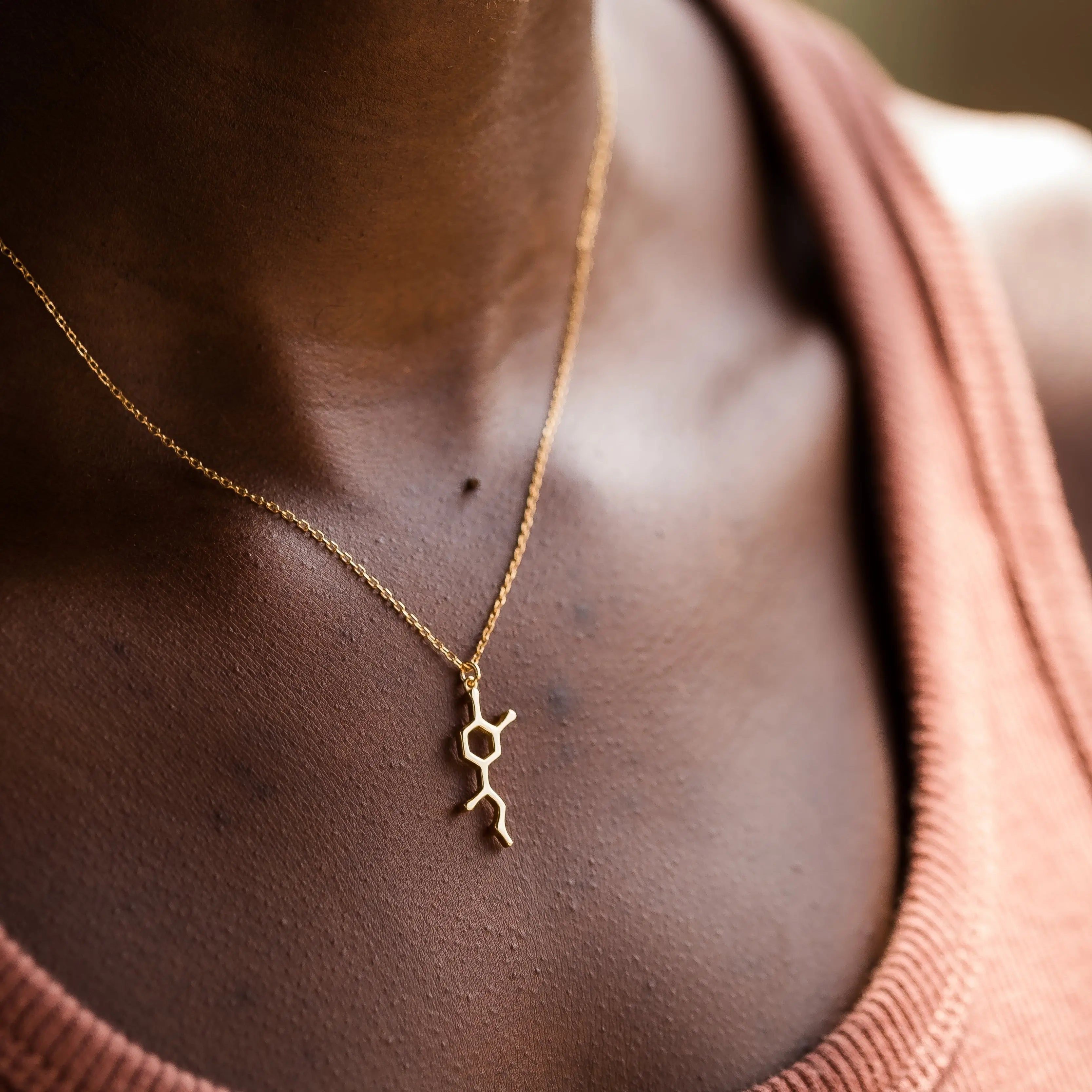 Model wearing adrenaline molecule necklace in gold - chemistry inspired jewellery for science lovers 