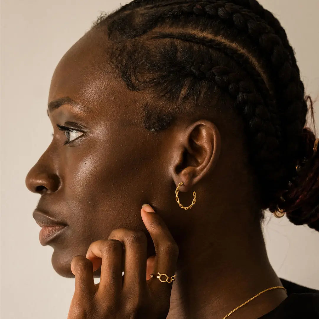Model wearing DNA double helix hoop earrings in gold - chemistry inspired jewellery for science lovers 