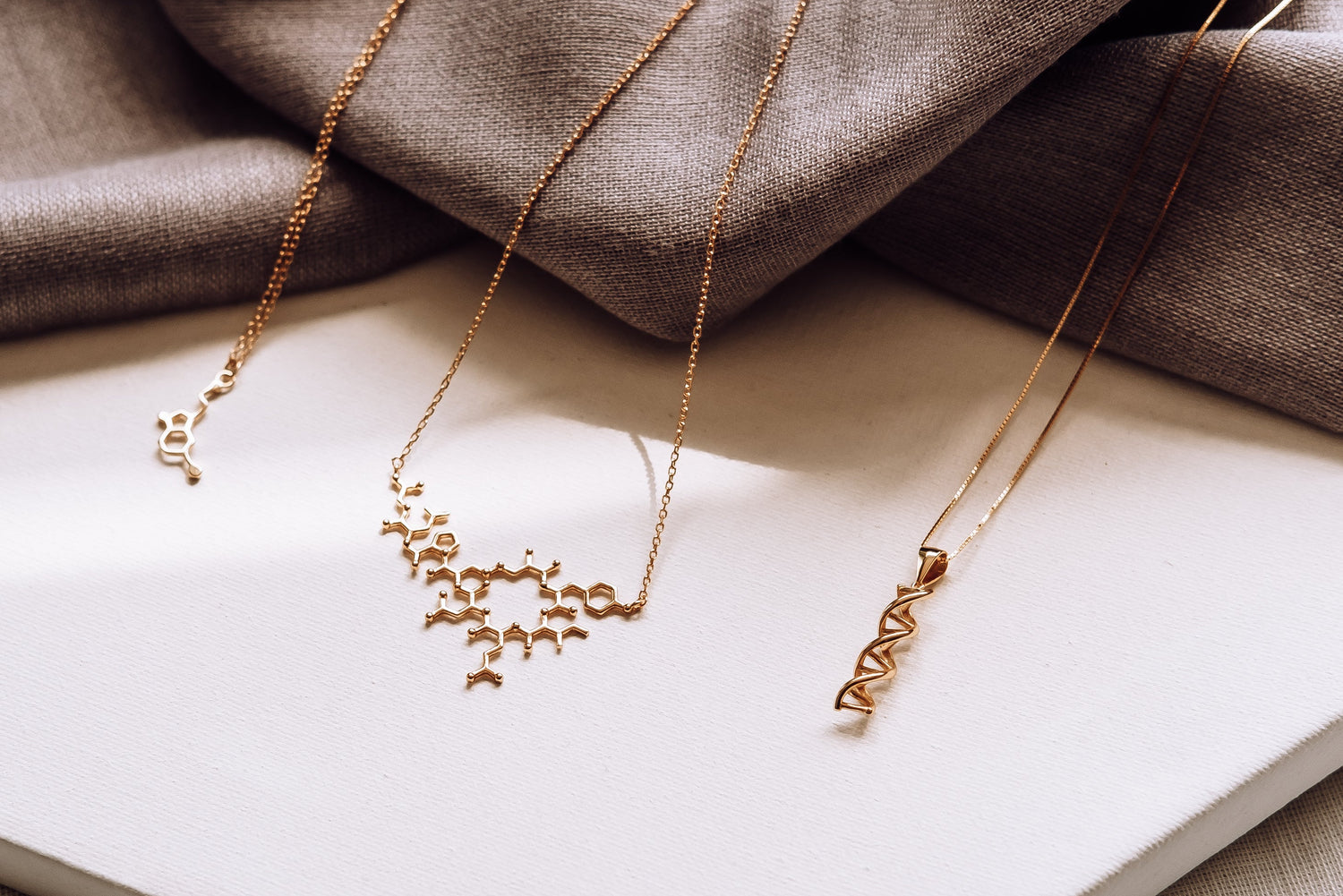 Two gold necklaces on a white book with a brown fabric background