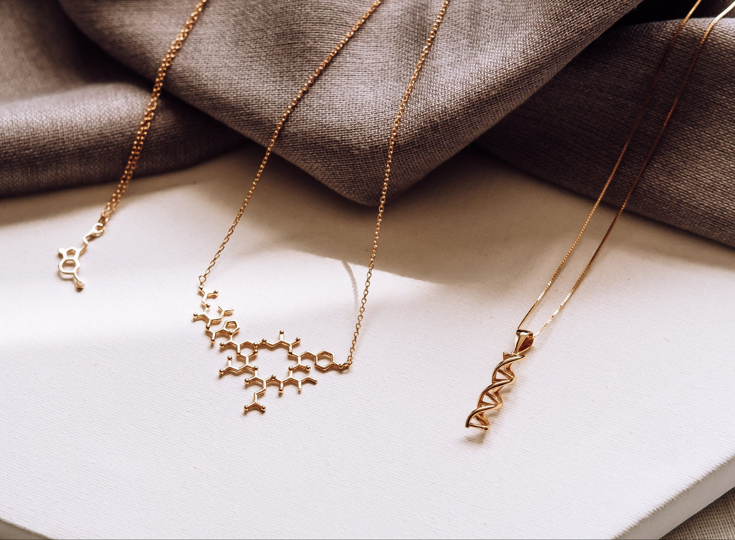 Two gold necklaces on a white book with a brown fabric background