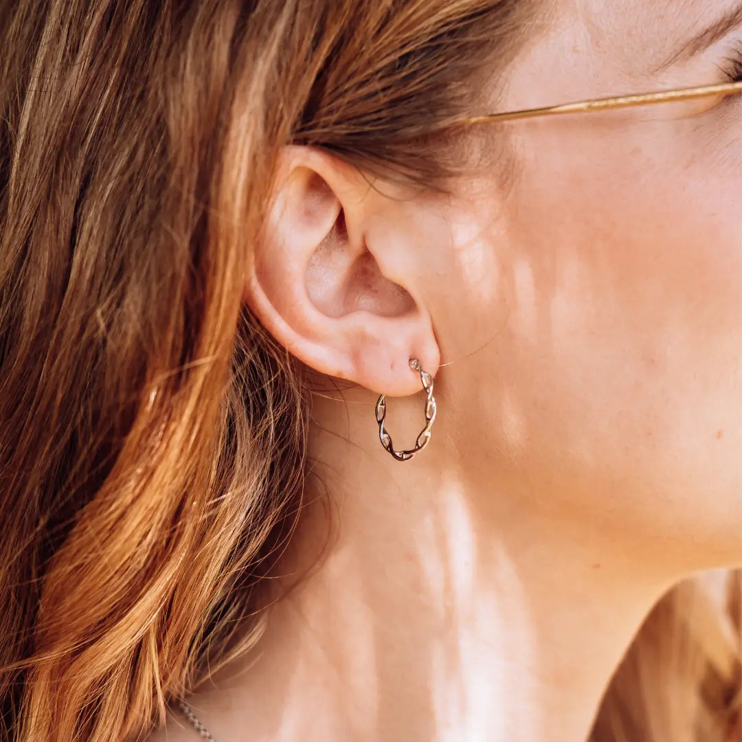 Model wearing DNA double helix hoop earrings in silver - chemistry inspired jewellery for science lovers 