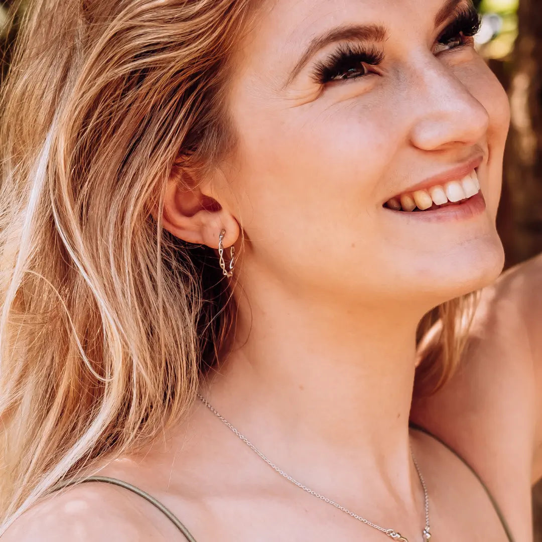 Model wearing DNA double helix hoop earrings in silver - chemistry inspired jewellery for science lovers 