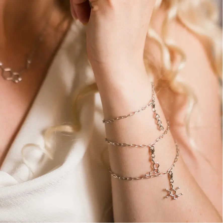 Model wearing caffeine molecule and serotonin molecule silver charm bracelet - chemistry inspired jewellery for science lovers 