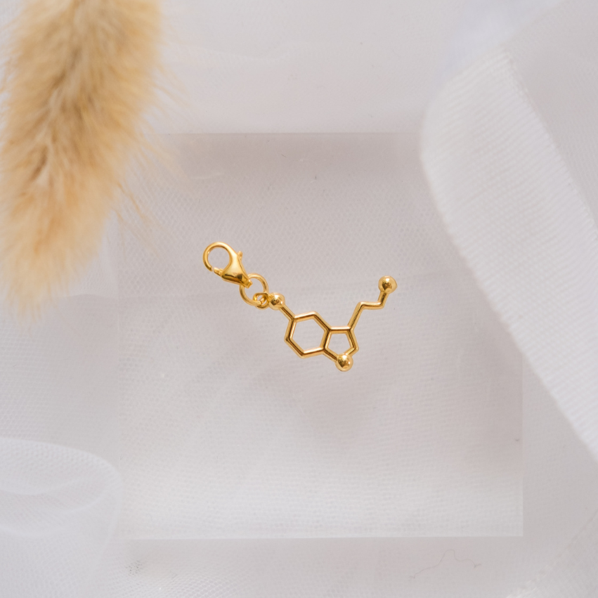 Gold molecule-shaped earring on a white background