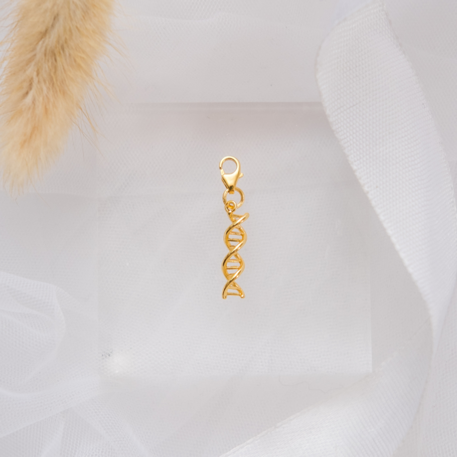 Gold DNA-shaped pendant on a white fabric background