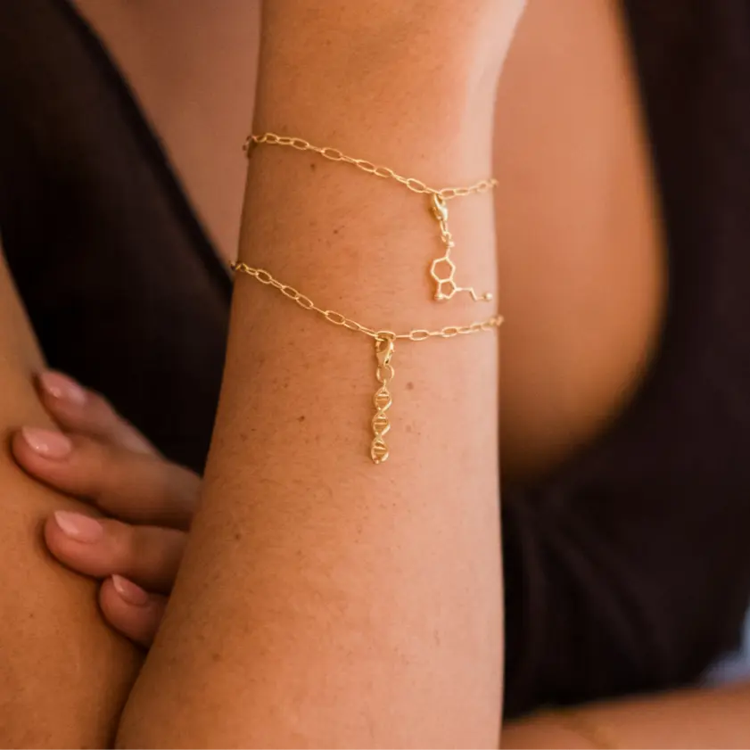 Model wearing DNA double helix gold charm bracelet - chemistry inspired jewellery for science lovers 