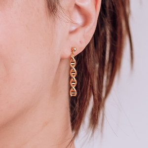 Model wearing gold helix earrings shaped like DNA double helix | Science-inspired jewellery gift for chemistry lovers