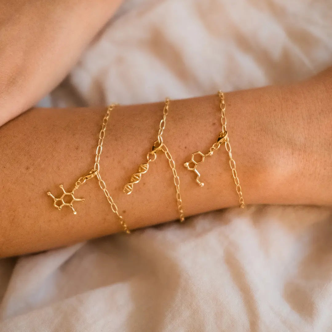 Model wearing serotonin molecule gold charm bracelet - chemistry inspired jewellery for science lovers 