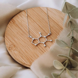 Caffeine molecule necklace in silver on a wooden background - chemistry inspired jewellery gift for coffee lovers 