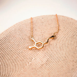 Dopamine molecule necklace in gold on a wooden background - chemistry inspired jewellery for science lovers 