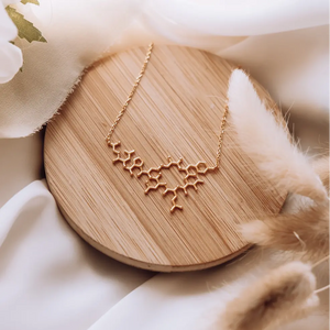 Oxytocin molecule necklace symbolising love and bonding on a wooden background with feathers