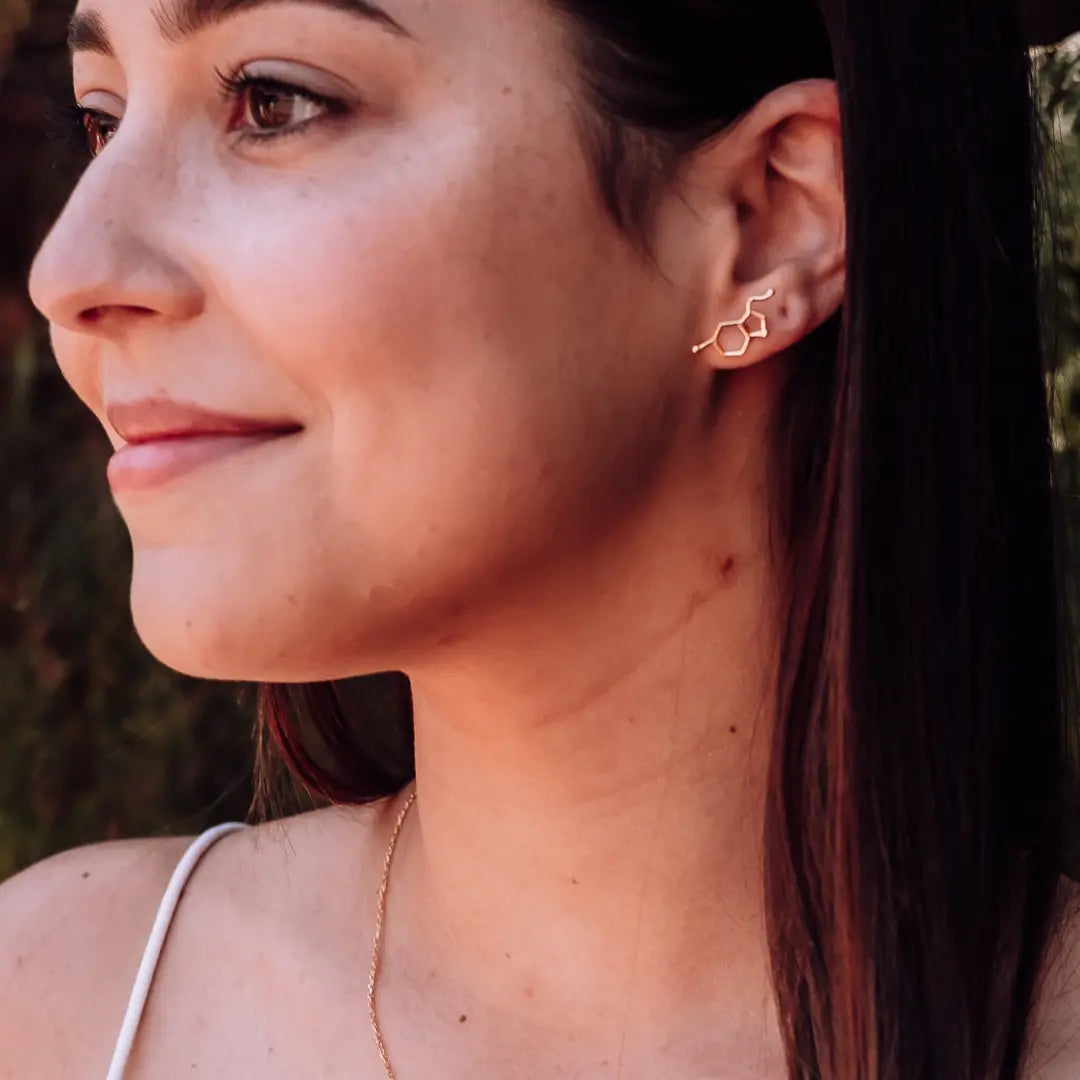 Model wearing serotonin molecule earrings in gold - chemistry inspired jewellery for science lovers 