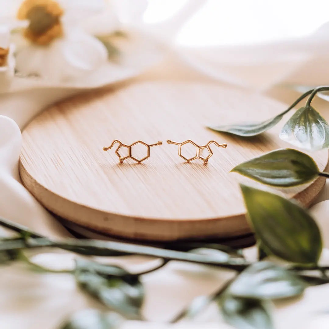 Serotonin molecule earrings in gold on a wooden background - chemistry inspired jewellery for science lovers 