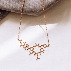 Gold oxytocin molecule necklace on white background