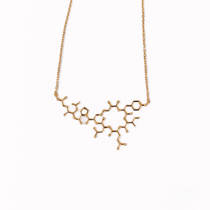 Gold oxytocin molecule necklace on white background